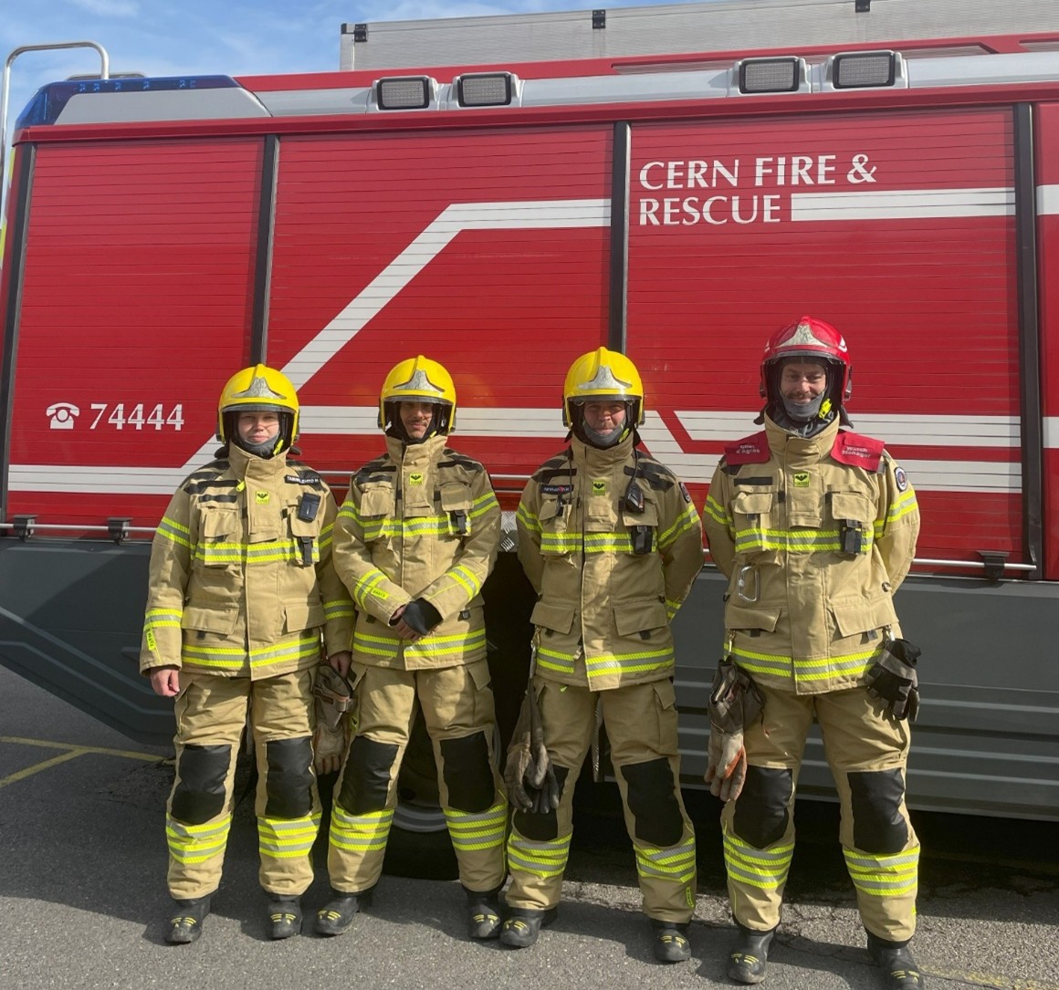 Four CFRS firefighters wearing the new, distinctly less orange, uniform in front of the fire engine.